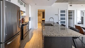 A modern kitchen with a large island, stainless steel appliances, and a minimalist design. - Les Immeubles Charlevoix - 760415 (Ville de Québec)
