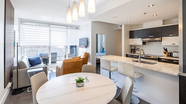 Una cocina moderna con una isla central, electrodomésticos integrados e iluminación colgante.