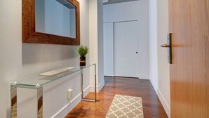 A hallway with a glass console table, a wooden door, and a white door in the background. - Les Immeubles Charlevoix - 760506 (Ville de Québec)