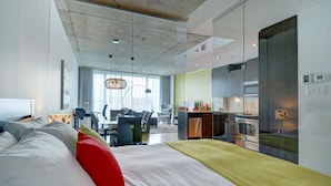 Ein modernes Hotelzimmer mit einem großen Bett, einem Schreibtisch und einer Küchenzeile.