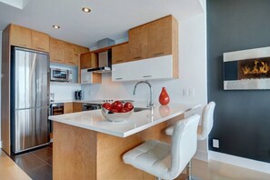 Een moderne keuken met houten kastjes, roestvrijstalen apparatuur en een centraal eiland met een schaal rode appels.