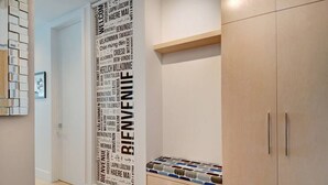 Un couloir orné d’une enseigne verticale accueillante, affichée en plusieurs langues, d’une armoire en bois et d’une petite étagère sur laquelle sont disposés divers objets.