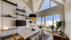 Una cocina moderna con una mesa de comedor alargada, estanterías empotradas y ventanas amplias con vistas al exterior.
