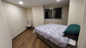 Une chambre à coucher avec un lit, une chaise, une fenêtre et un plancher en bois.