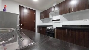 Une cuisine moderne avec des meubles de rangement en bois foncé, un plan de travail en acier inoxydable et une cuisinière à gaz.