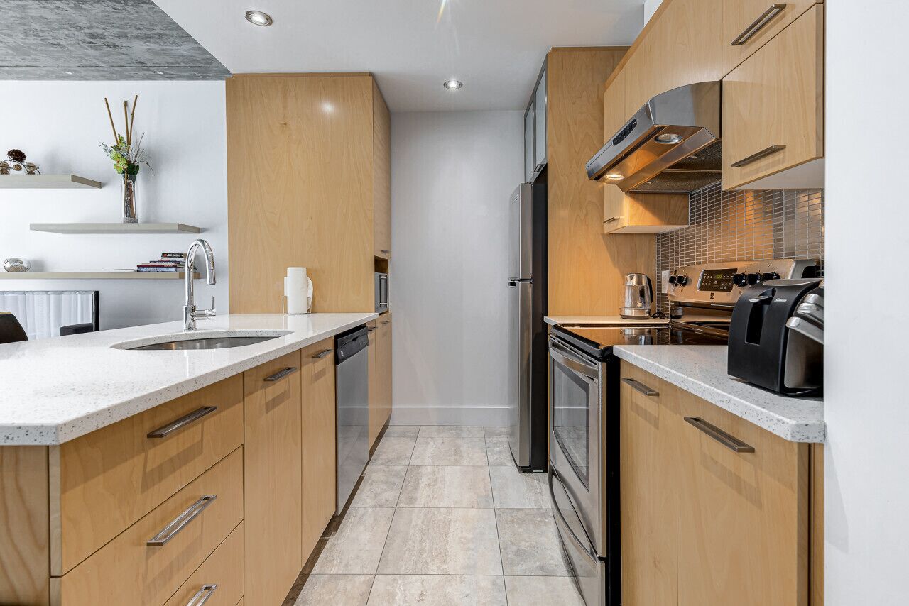 Une cuisine moderne avec des meubles en bois, des appareils en acier inoxydable et un plan de travail en granit.