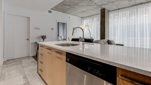 Una cocina moderna con una isla grande, lavavajillas integrado y un comedor con sofá y sillas.