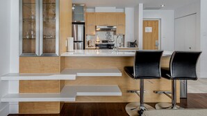 Una cocina moderna con una isla central, electrodomésticos de acero inoxidable y una zona de comedor con taburetes de bar.
