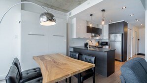 A modern kitchen with a central island, black cabinetry, and stainless steel appliances. - Les Immeubles Charlevoix-Le 760631 (Québec)