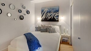 Ein modernes Schlafzimmer mit einem großen Bett, einem Wandspiegel und einem Gemälde.