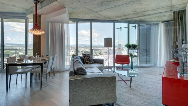 Un salón moderno con comedor, ventanas amplias y vista a la ciudad.
