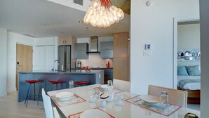 Una cocina moderna con una isla central, taburetes de bar y una mesa de comedor para cuatro.