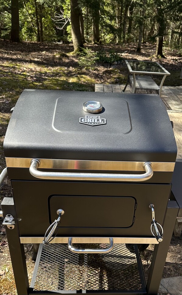 A portable grill with a digital thermometer on top, a handle, and a mesh vent.