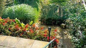 Üppiger Garten mit vielfältigen Pflanzen und einem gepflasterten Weg.
