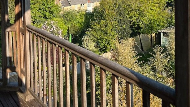 Ein Holzbalkon mit Blick auf eine Küstenstadt und das Meer.