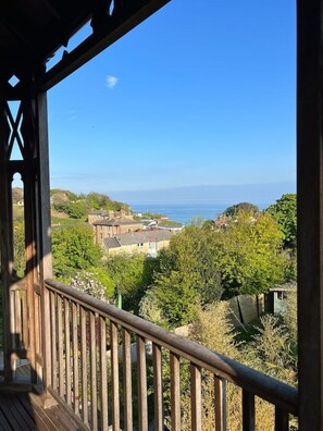 Ein Holzbalkon mit Blick auf eine Küstenstadt und das Meer.