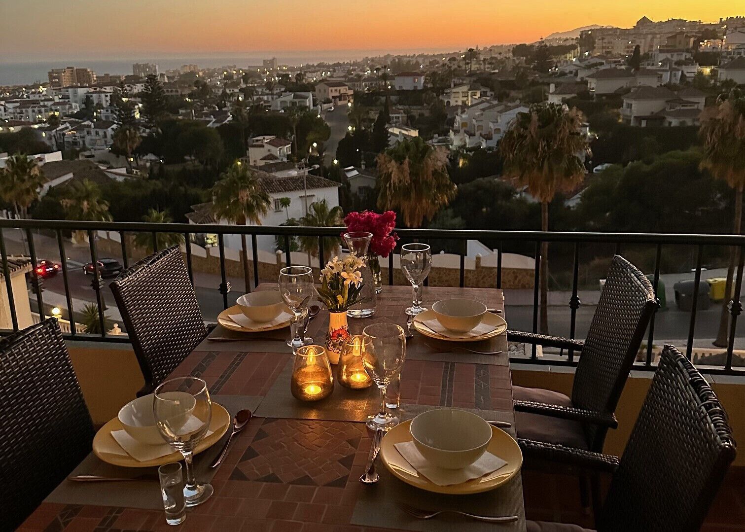 A table set for two with a view of a cityscape at sunset.