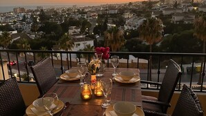 A table set for two with a view of a cityscape at sunset. - P12 Riviera Golf - Apartment (Mijas Costa)
