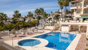 A swimming pool with a tiled deck, lounge chairs, and umbrellas. - P12 Riviera Golf - Apartment (Mijas Costa)