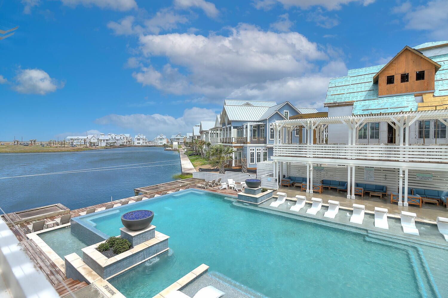 Un hôtel situé au bord de l’eau, doté d’une piscine, d’un espace extérieur aménagé et offrant une vue sur l’eau.