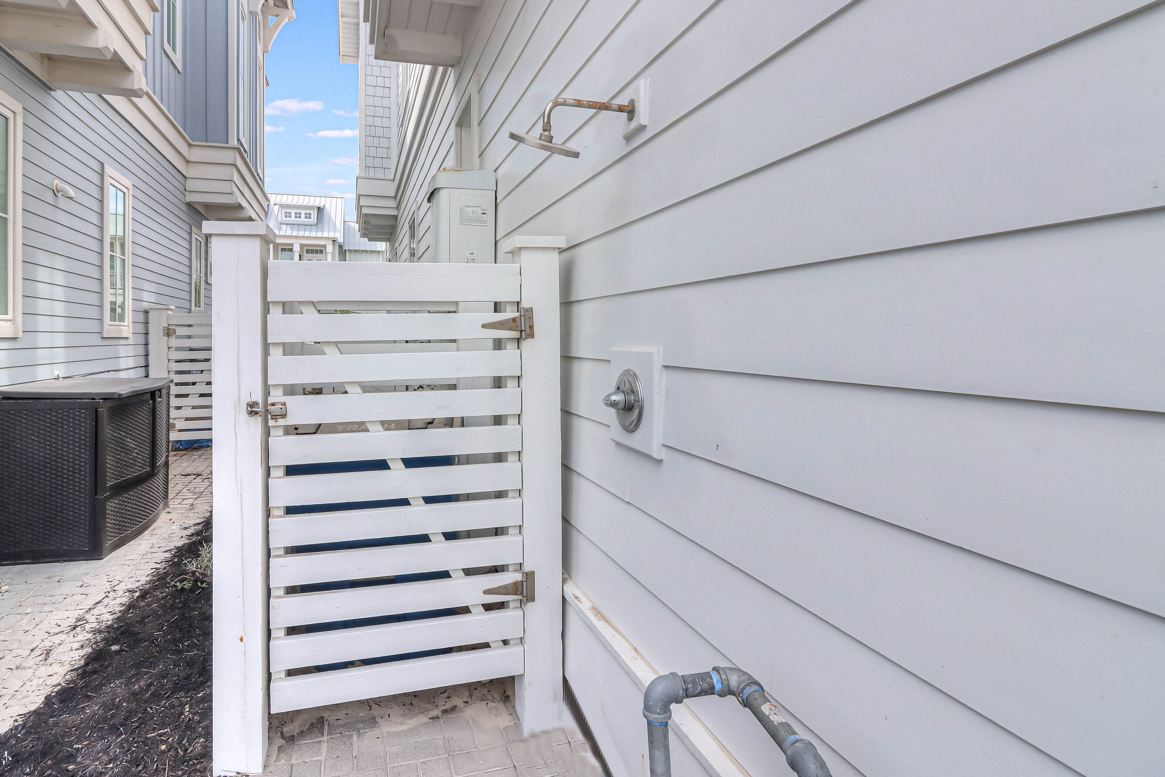 A gated entryway with a white gate, a metal door, and a wall-mounted electrical box.
