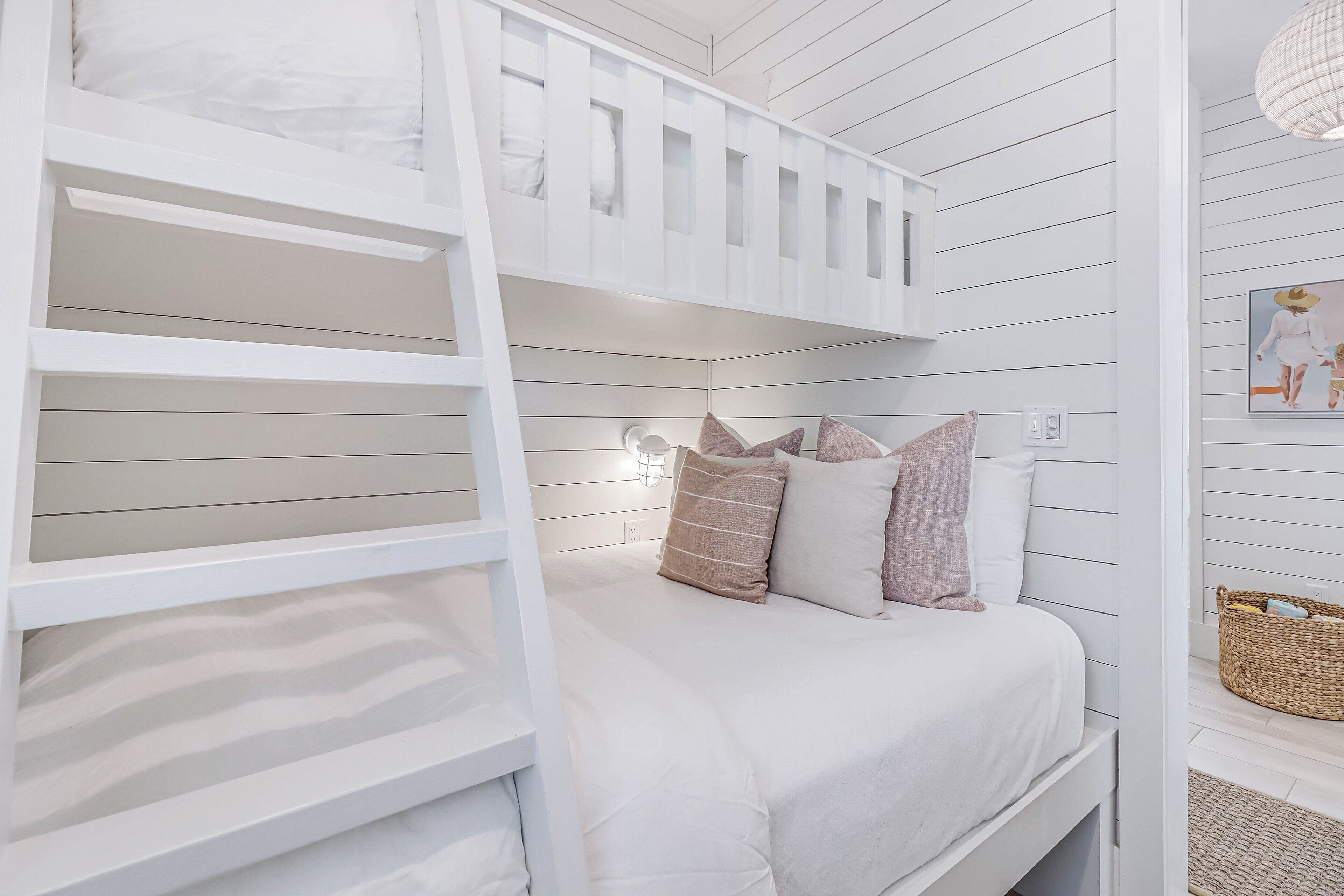 Una cama litera con escalera, una mesita de noche y una lámpara de pared.
