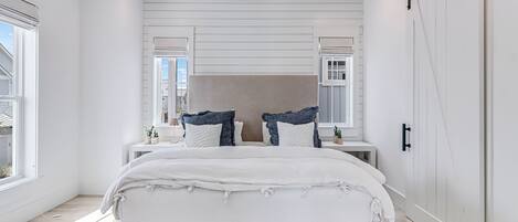 Un dormitorio con una cama grande, un aparador, un espejo y una puerta corrediza.