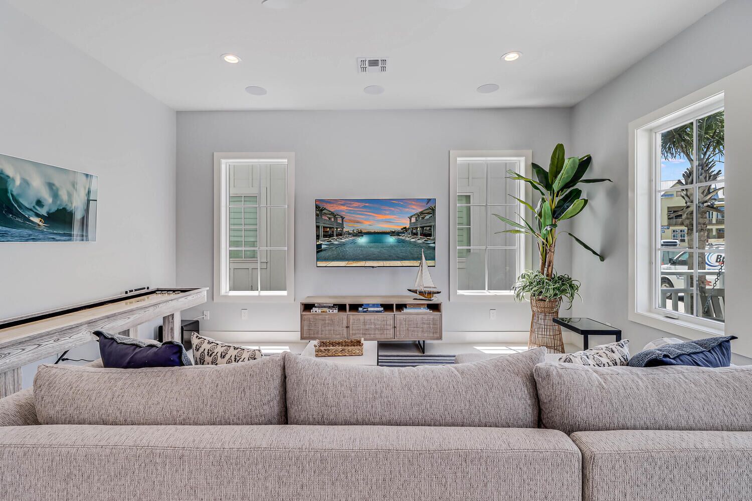 A modern living room with a large flat-screen TV, a sofa, a coffee table, and a potted plant.