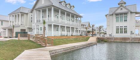 A waterfront property with a wooden deck, a canal, and white buildings with balconies.