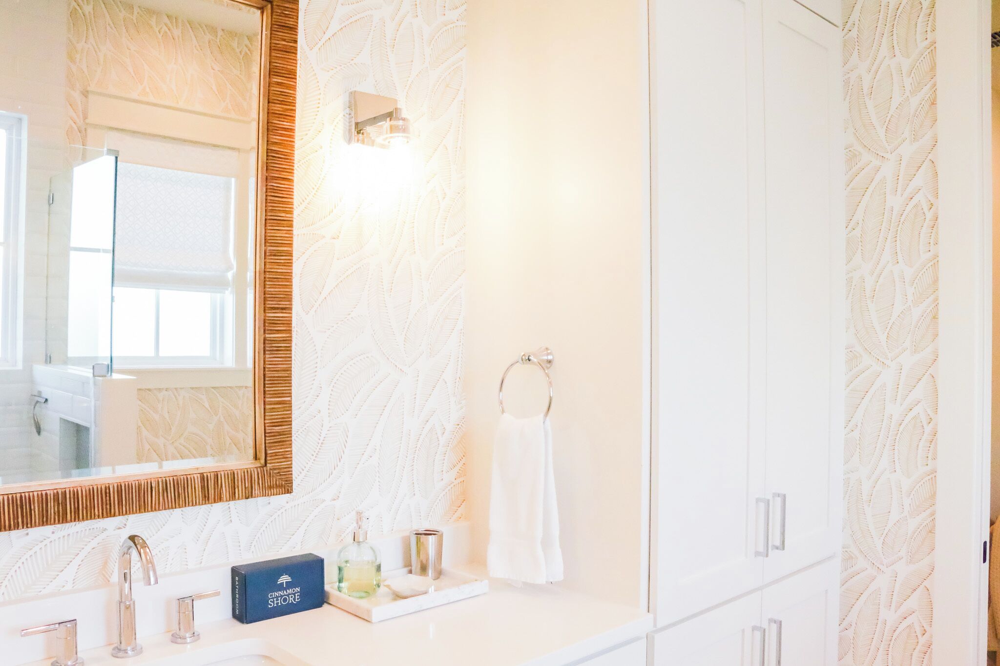 A bathroom with a large mirror, a sink with two faucets, a towel rack, and a decorative wall panel.