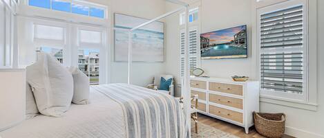 A bedroom with a large bed, a dresser, a basket, and a painting.