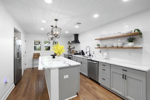 Cozinha moderna com ilha central, armários cinza e piso de madeira.