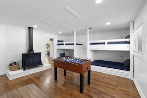 A room with a foosball table, bunk beds, a fireplace, and a white brick wall. - Lakefront, Views, Private Dock, Boat Rental, Bunks, Near Clemson, Kayaks! (Starr)