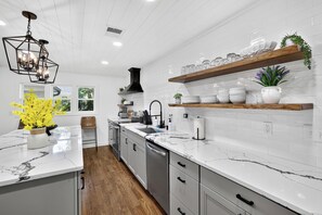 A modern kitchen with white cabinetry, a marble countertop, and a built-in oven. - Lakefront, Views, Private Dock, Boat Rental, Bunks, Near Clemson, Kayaks! (Starr)