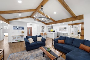 A spacious living area with two sofas, a coffee table, and a kitchen in the background. - Lakefront, Views, Private Dock, Boat Rental, Bunks, Near Clemson, Kayaks! (Starr)