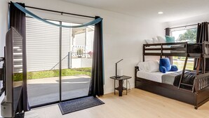 Een kamer met een stapelbed, een bureau met een lamp en een glazen schuifdeur die uitkomt op een terras.