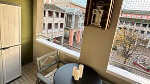 Un petit balcon avec une table, des chaises et un réfrigérateur.