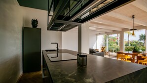 A modern kitchen with a large island, a built-in oven, and a dining area with yellow chairs and a table. - Villa With Private Pool Terraforte Suites Wellness Activities (Marina di Ragusa)