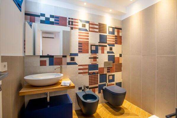 Ein modernes Badezimmer mit einem großen Waschbecken, einem Bidet und einer Wand mit geometrischen Mustern.