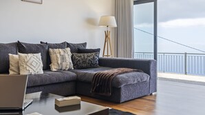 Ein modernes Wohnzimmer mit einem grauen Ecksofa, einem Holztisch und einer Stehlampe.