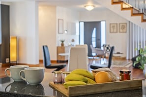A kitchen counter with a tray of bananas, bread, and a jar of jam.