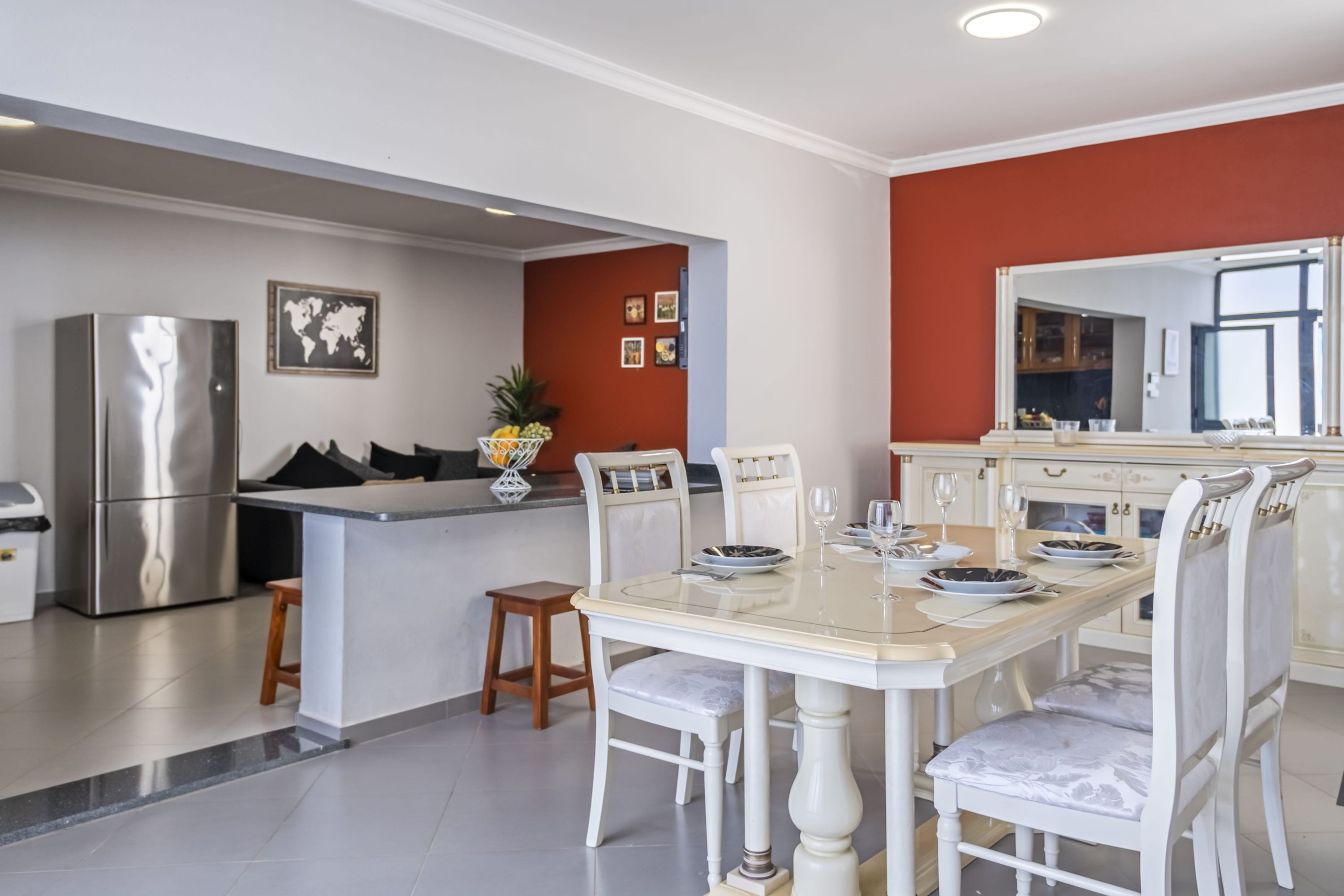 Een moderne keuken met een centraal eiland, een roestvrijstalen koelkast en een eethoek met witte stoelen en een tafel voor vier personen.
