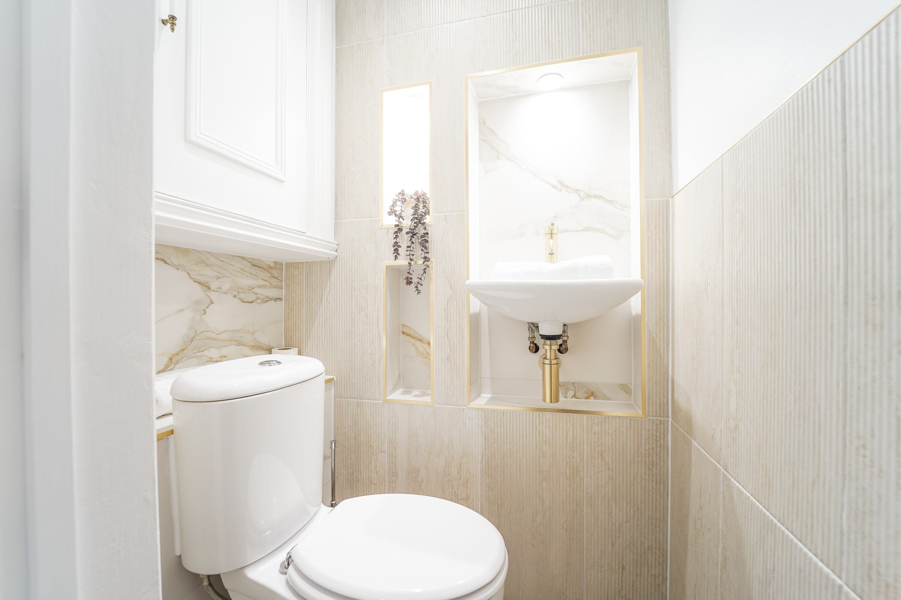 Een badkamer met toilet, wastafel en spiegel.