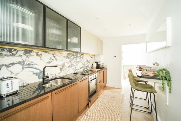 Enjoy cooking in this well-equipped kitchen with an oven, stainless steel sink, and wooden cabinets.