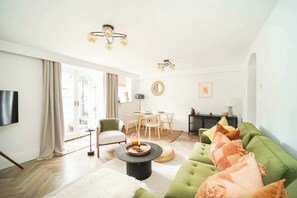 Relax in this stylish living room with a green sofa, round coffee table, and flat-screen TV.