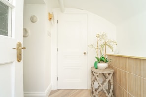 A traditional door with a console table and potted orchid greets you in this serene hallway.