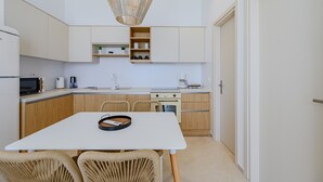 A compact kitchen with white cabinets, a microwave, a coffee maker, and wicker chairs. - Pyrgos Exquisite villa 3 ,private pool,South Crete (Plakias)