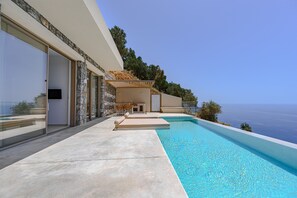 A modern poolside area with a clear view of the sea, a covered seating area, and a stone facade. - Pyrgos Exquisite villa 4 ,private pool,South Crete (Plakias)