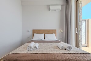 A hotel room with a bed, white pillows, a brown quilted bedspread, a white blanket, and a window with curtains. - Pyrgos Exquisite villa 5 ,private pool,South Crete (Plakias)