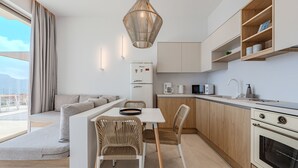 A modern kitchen with white cabinetry, a dining area with a white table and wicker chairs, and a built-in oven. - Pyrgos Exquisite villa 5 ,private pool,South Crete (Plakias)